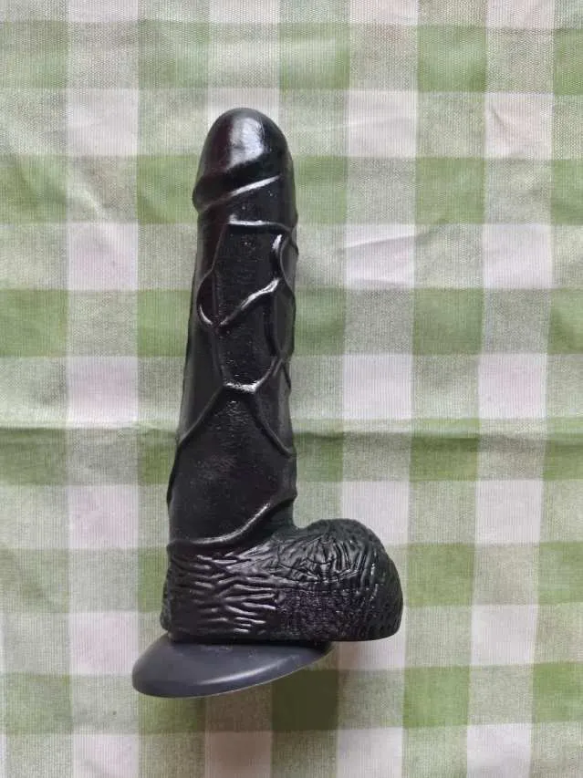 KY32 black realistic silicone dildo photographed upright on a checked fabric background