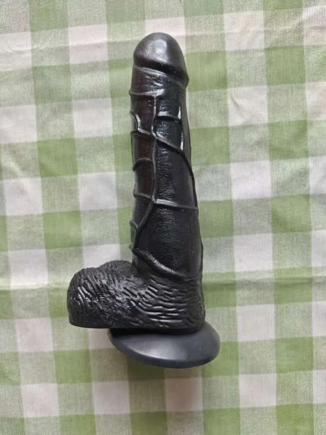 Angled real-life photo of the KY32 black dildo showing its textured shaft and suction base